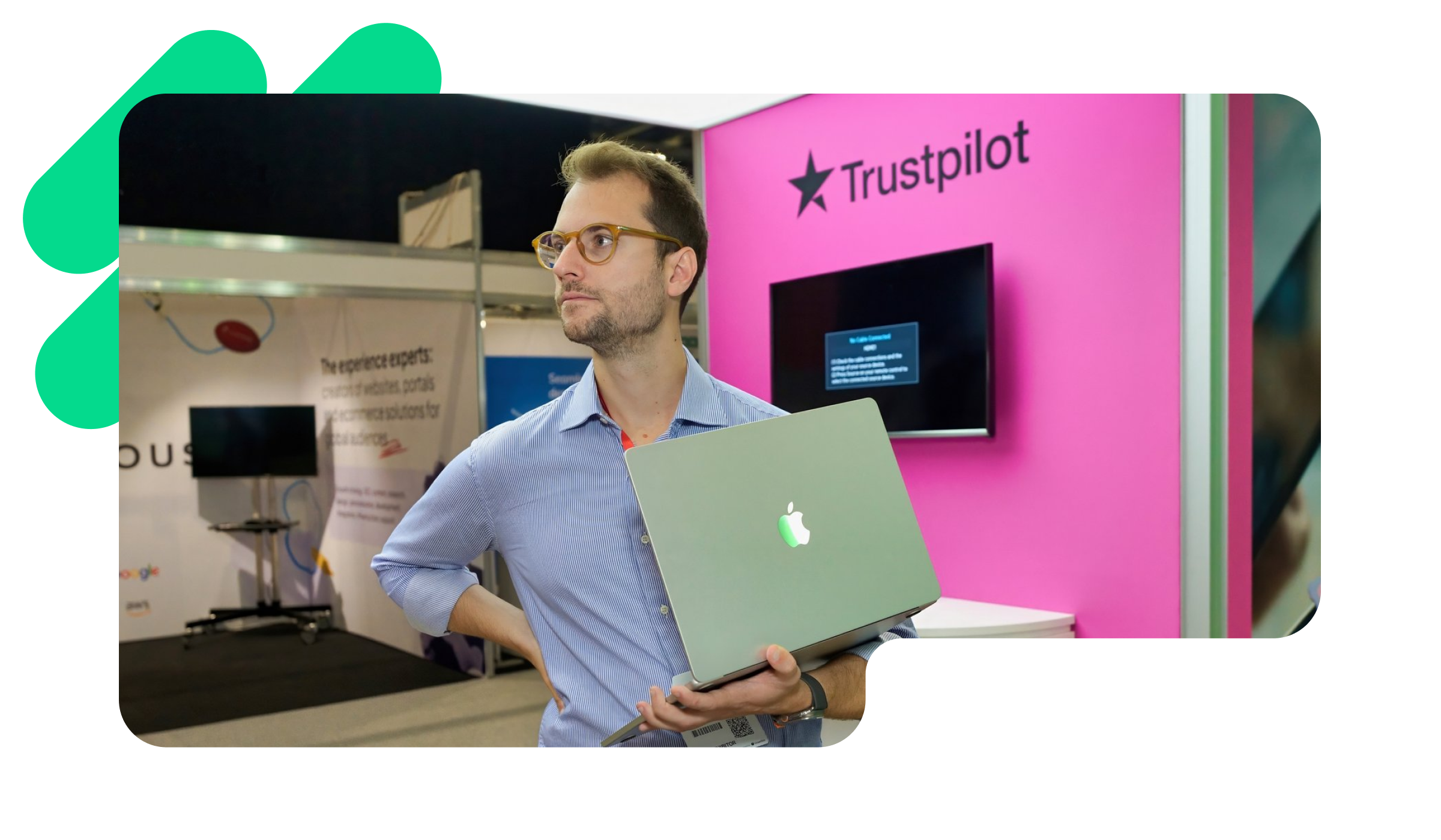 A photo of a Trustpilot employee standing in the Trustpilot office with his Macbook in his hands