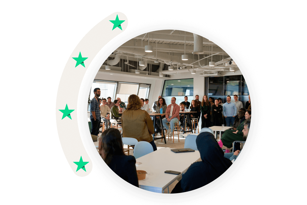 A photo in a circle shape showing Trustpilot employees participating in a meeting.